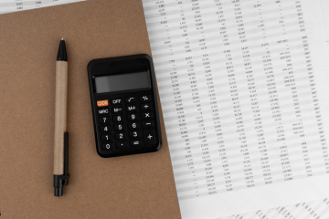 An organized workspace featuring a desk with financial documents, a laptop displaying accounting software, and a calendar with tax season marked. The image conveys a clean, prepared environment for handling tax season bookkeeping.