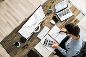 A professional bookkeeper organizing financial records on a modern desk with a laptop, reports, and charts. The backdrop features a bright office setting, symbolizing small business accounting solutions in South Florida.