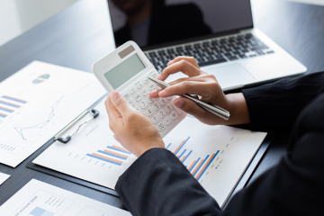 A professional office setting in Miami-Dade County with a certified bookkeeper working at a desk, surrounded by accounting tools like ledgers, calculators, and a laptop.